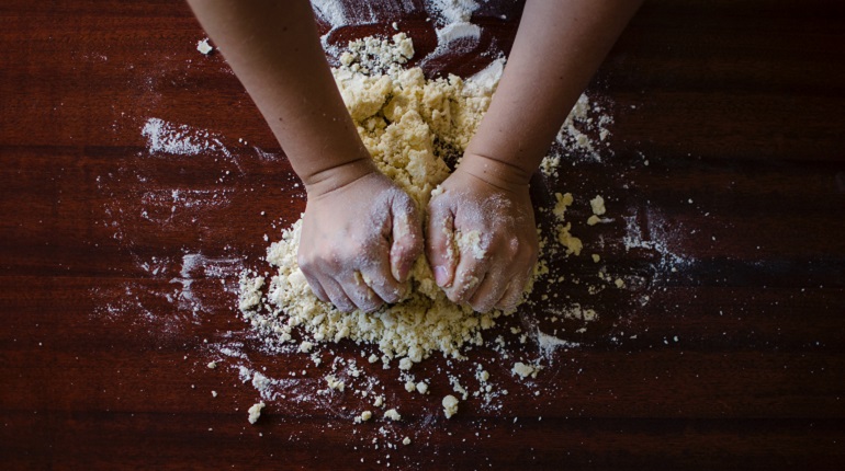Hands kneading dough on a table