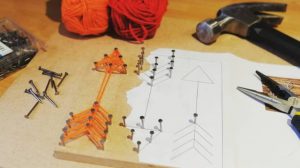 Board with string art of an orange arrow