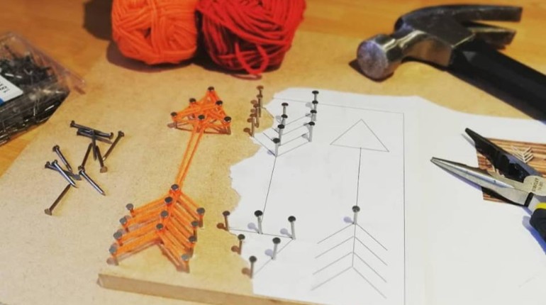 Board with string art of an orange arrow