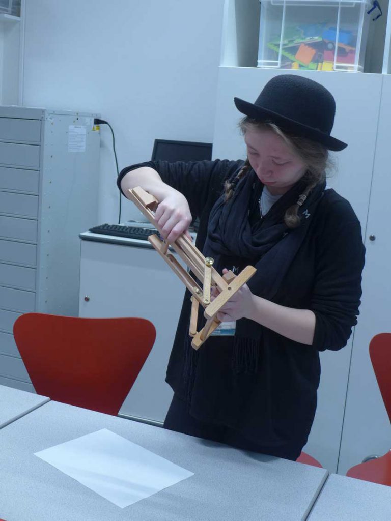 Student holding a small wooden table easel
