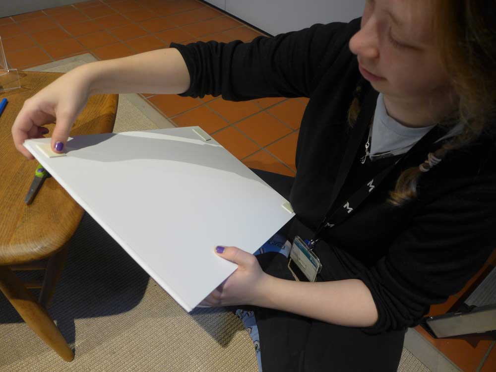 Student fixing tape to the back of a mounted image