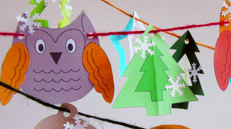 A colourful paper owl and christmas tree deocrated with snowflakes as part of a garland to make at the Second Sunday craft drop-in