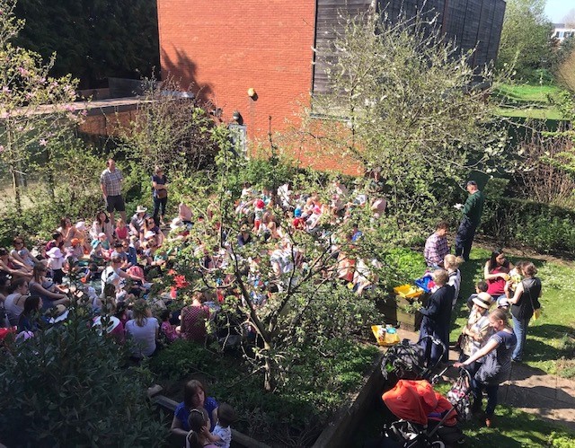 Group of adults and children in the MERL herb garden during Friday Fledglings snacktime