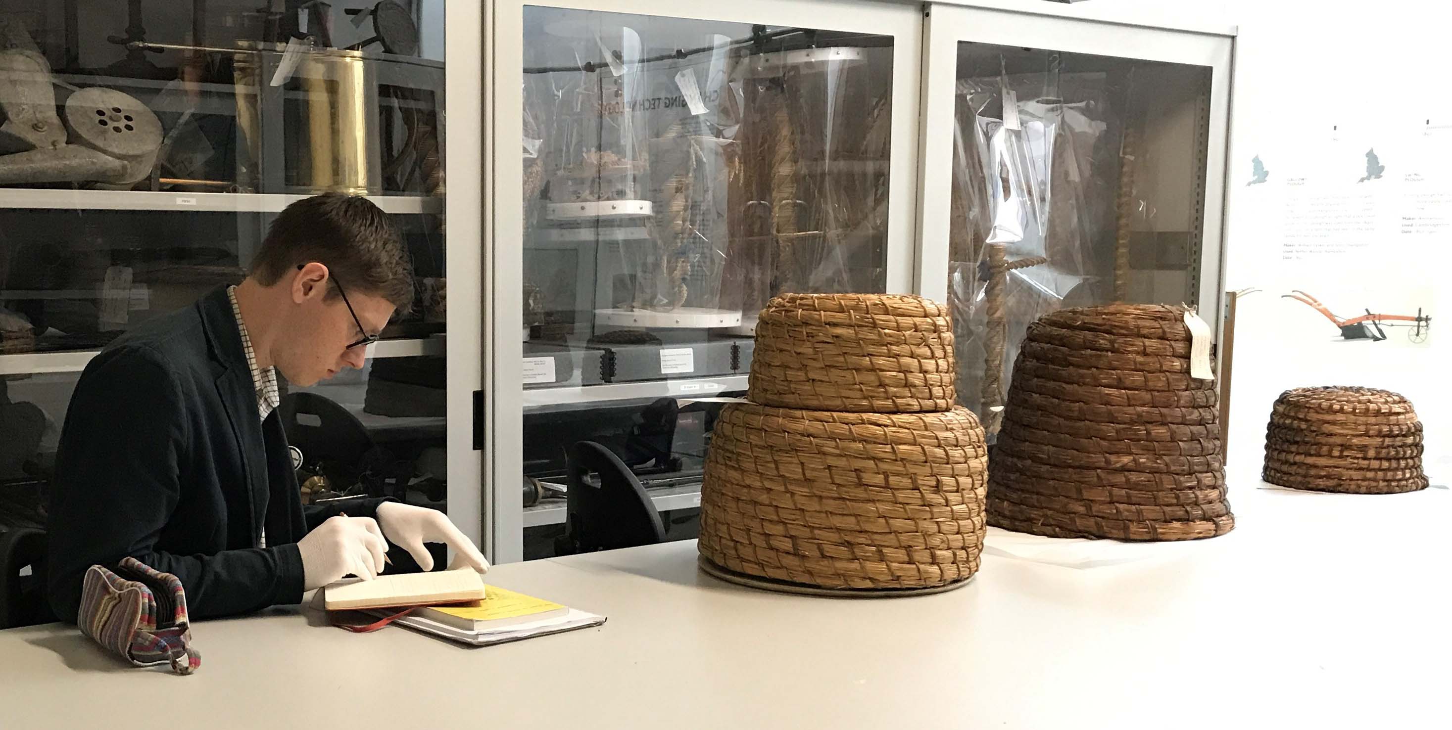 Poet Jack Thacker takes notes while examining bee skeps