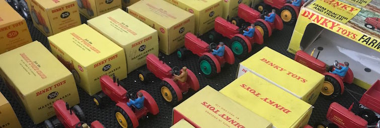 A drawer full of red toy tractors and yellow toy boxes