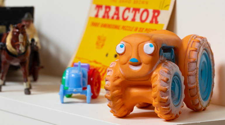 a bright orange toy tractor with facial features from the farm toys collection at the MERL