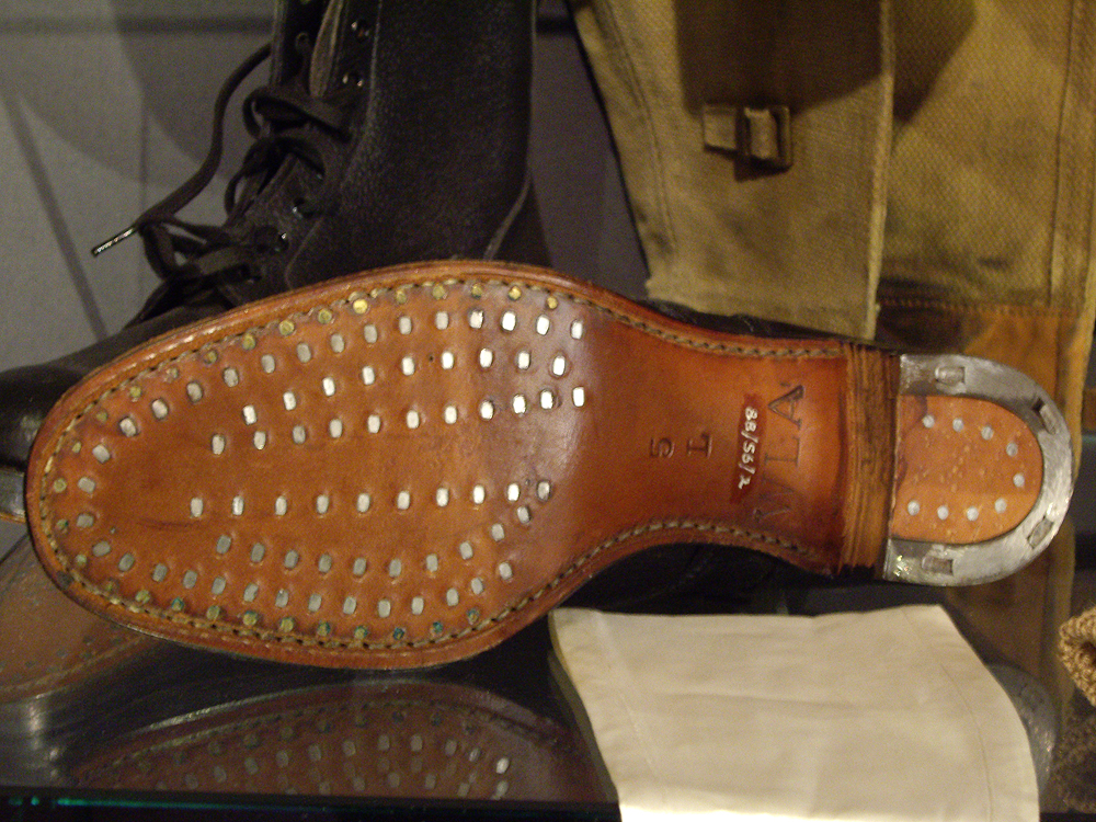 Land girls boots in a display cabinet, one with hob-nailed soles