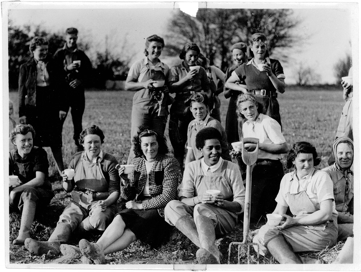 Land girl Amelia King wearing gumboots surrounded by other workers