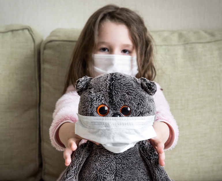 Little girl holding a teddy bear both wearing face masks