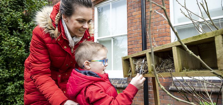 Woman and child looking at a bug hotel in the MERL garden
