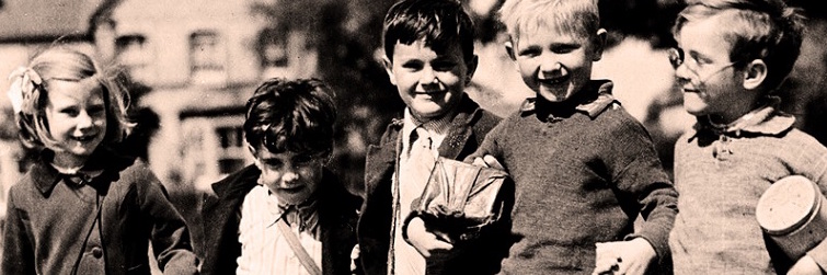 Five children/evacuees standing in a row, smiling in the sun