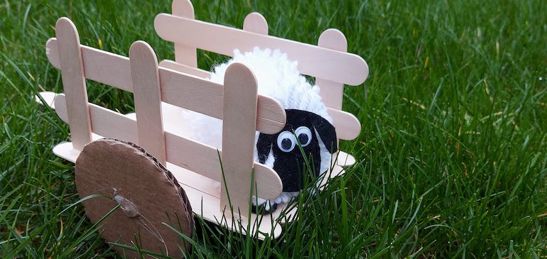 Pom pom sheep in a lolly pop cart in grass