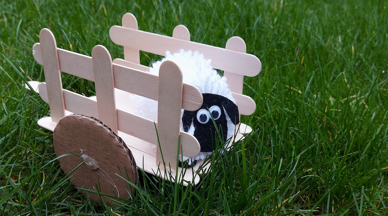 Pom pom sheep in a lolly pop cart in grass