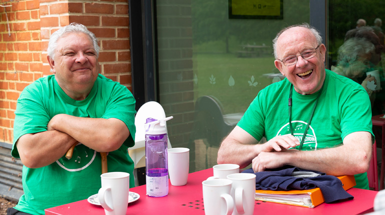 two men smiling as they sit outside in the MERL cafe