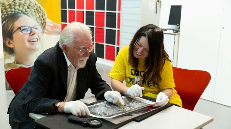 Two people looking at a collection object at The MERL