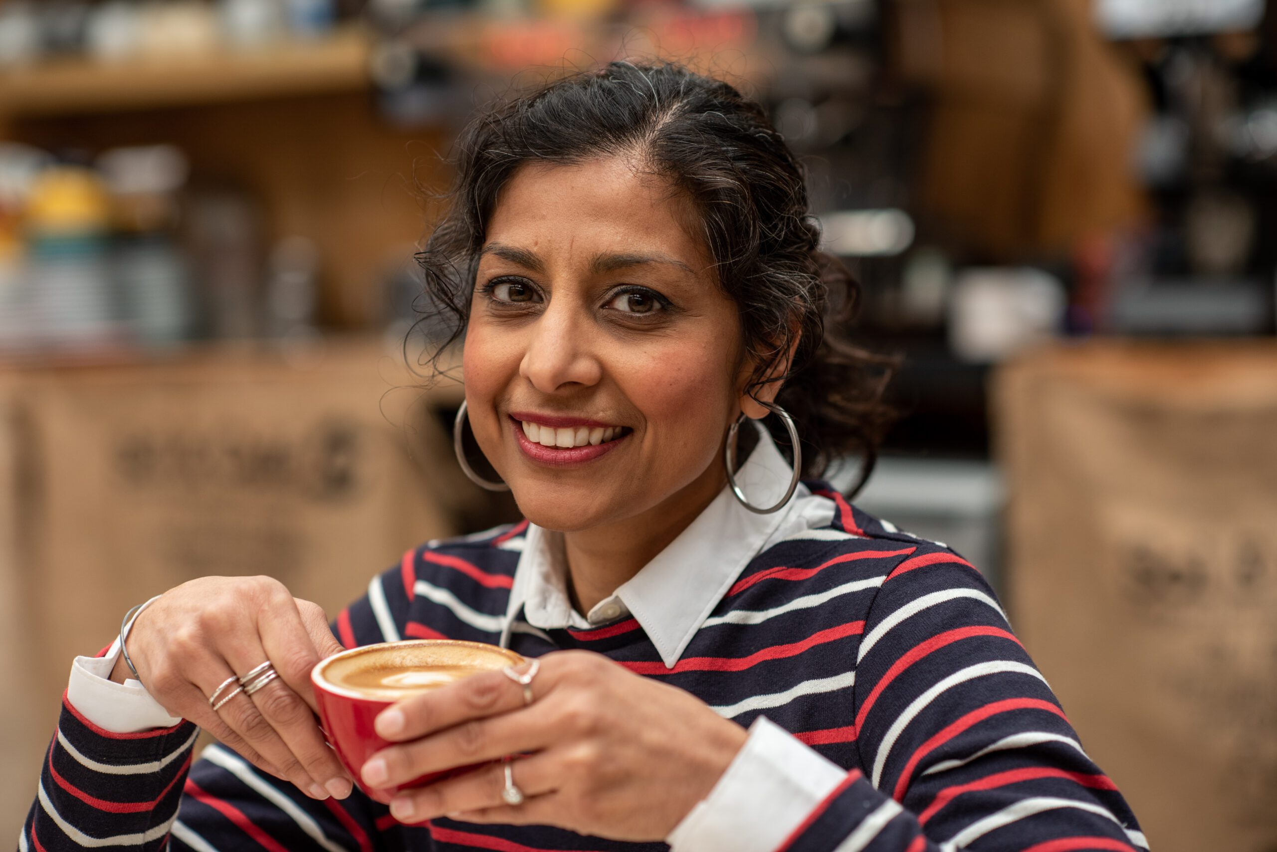 Dr Anjana Khatwa holding a coffee.