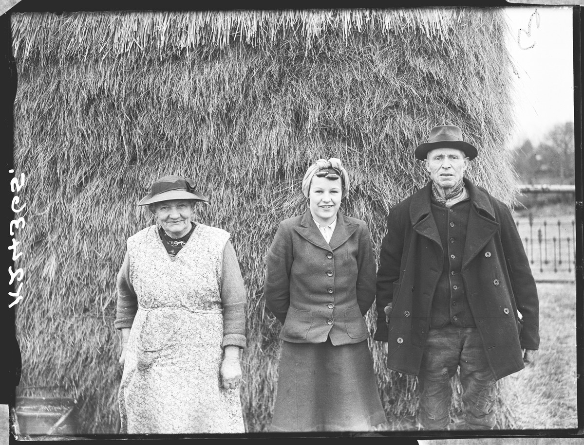 Two women and a man, in old farming clothes.