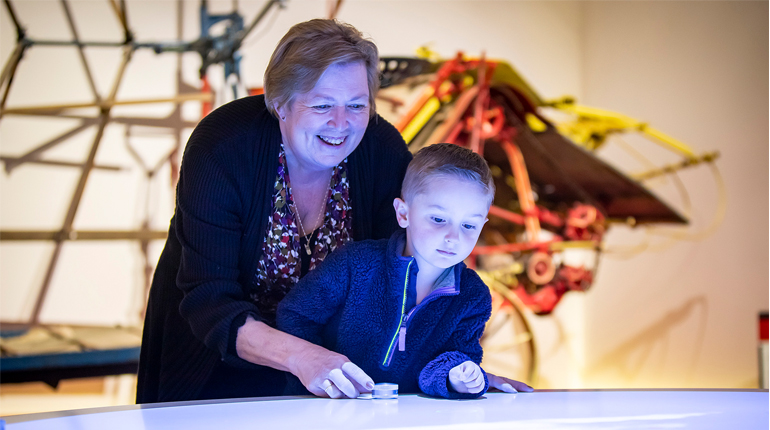young child and carer play on adigital interactive in the MERL galleries