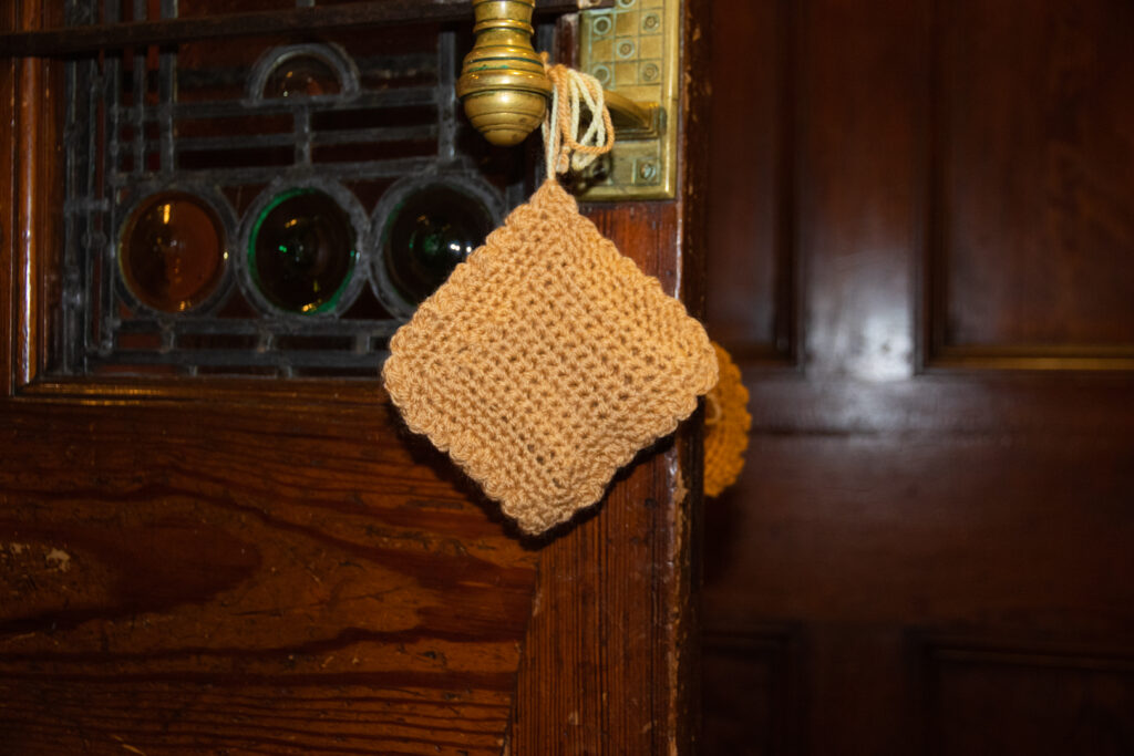 A knitted biscuit hanging from a door handle.