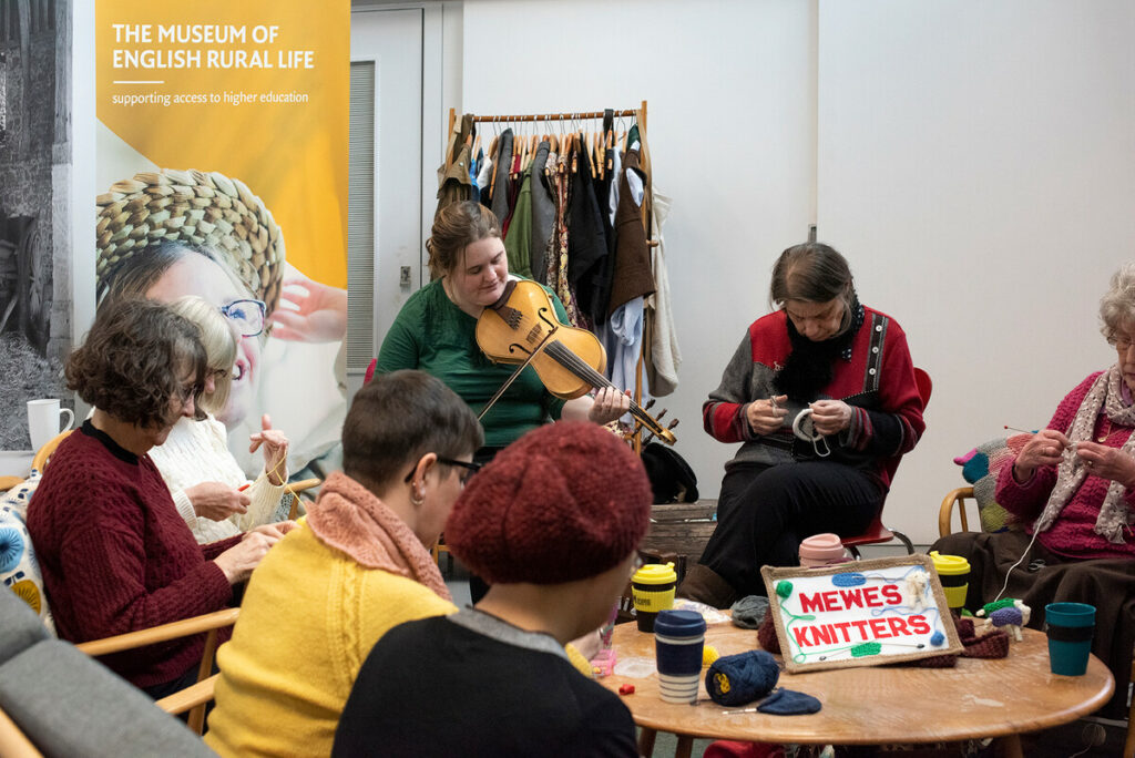 Jackie Oates plays music in the company of the Mewes Knitters, The MERL's resident knitting group.