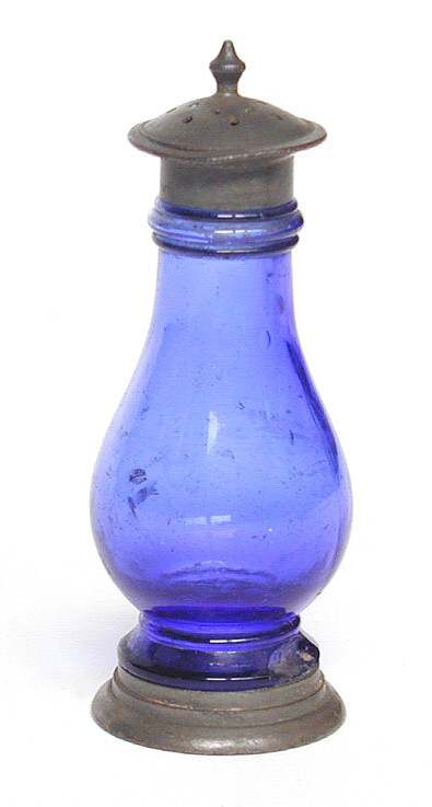 Little is known of the origin of this pepper pot. It is made of blue glass and has a pewter top and base. Pewter was traditionally used for condiment sets.