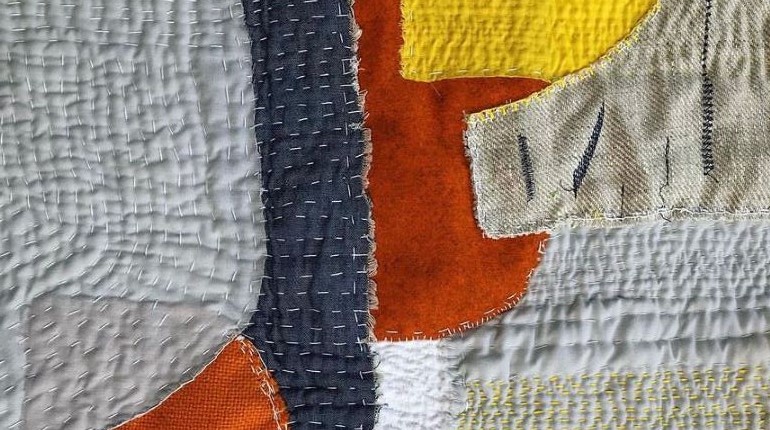 Details of a quilt made out from grey, blue, orange, yellow and white material