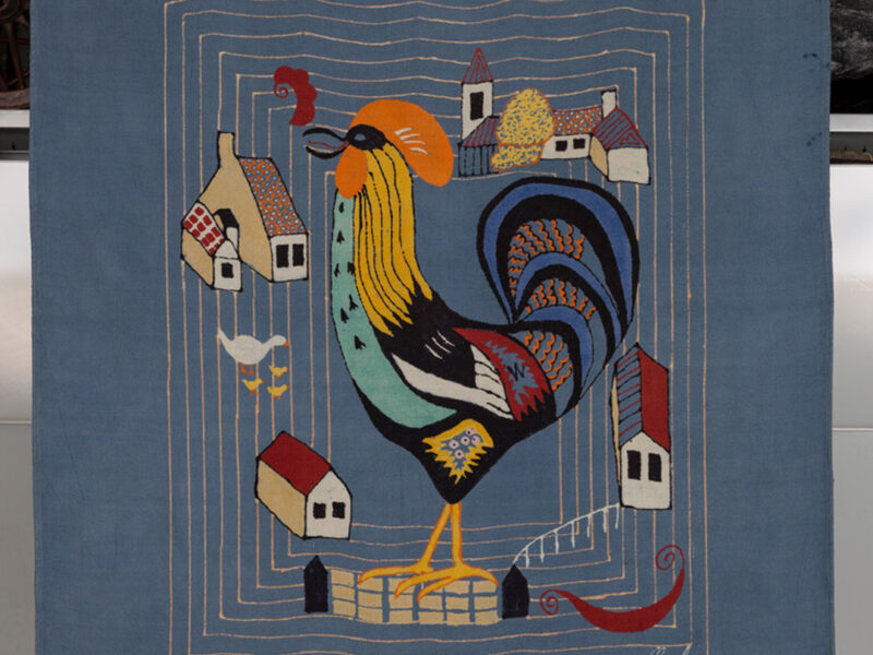 Wall hanging entitled 'Cockerel' designed, painted and dyed by Michael O'Connell, under the name Mael Fabrics. The blue rayon block printed panel depicts a cockerel in a farmyard. It was made circa 1950. Michael O'Connell worked with rayon and used a combination of batik and resist dyeing techniques to create his designs. He used specially formulated resists and dyes which were piped and dyed onto mordanted fabric then the whole fabric was dyed.