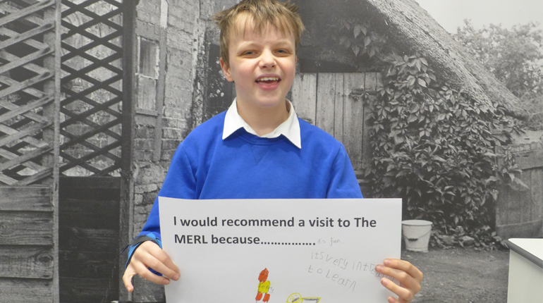 A child holds a piece of paper recommending why you should visit The MERL.