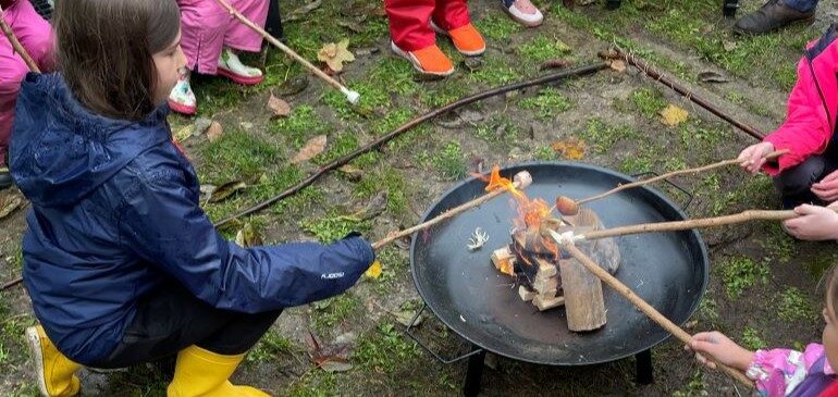 Families toasting marshmallows in the MERL garden during a Green Explorers session