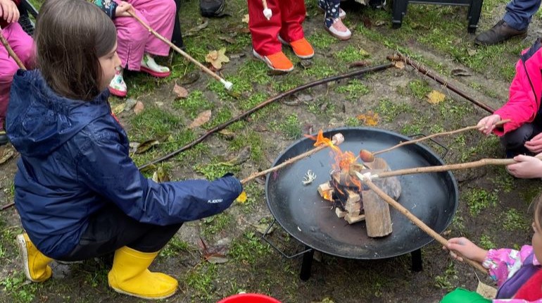 Families toasting marshmallows in the MERL garden during a Green Explorers session