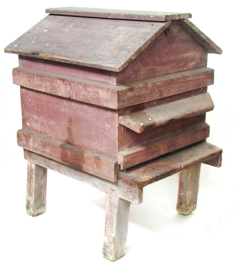 This is a wooden, red-painted bee hive which comes apart in three sections. The circular ventilator each end of the roof is made from a tin lid for 'Hudson's Extract Soap'. It was made by Mr Stewart, the father of Amelia Stewart, who died circa 1925. He was a carpenter and lived at South Green, Billericay, Essex. (MERL 82/27/1-3)