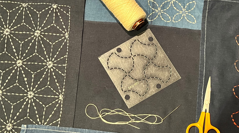 thread, fabric, scissors and a template laid out for japanese shashiko mending