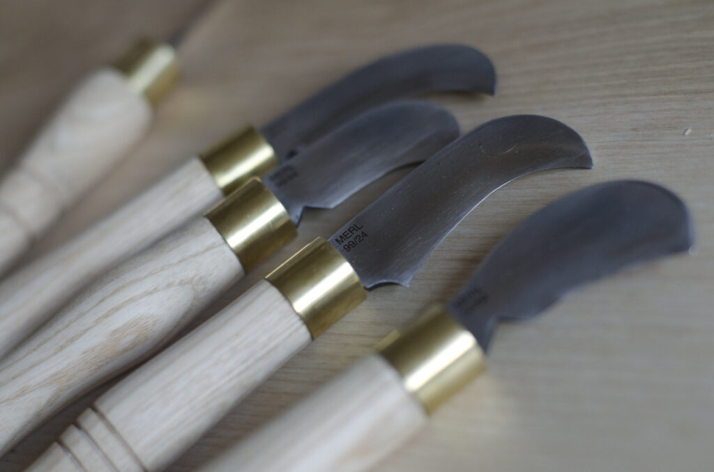 Detail showing domestic pruning knives inspired by billhooks sitting on a table top surface.