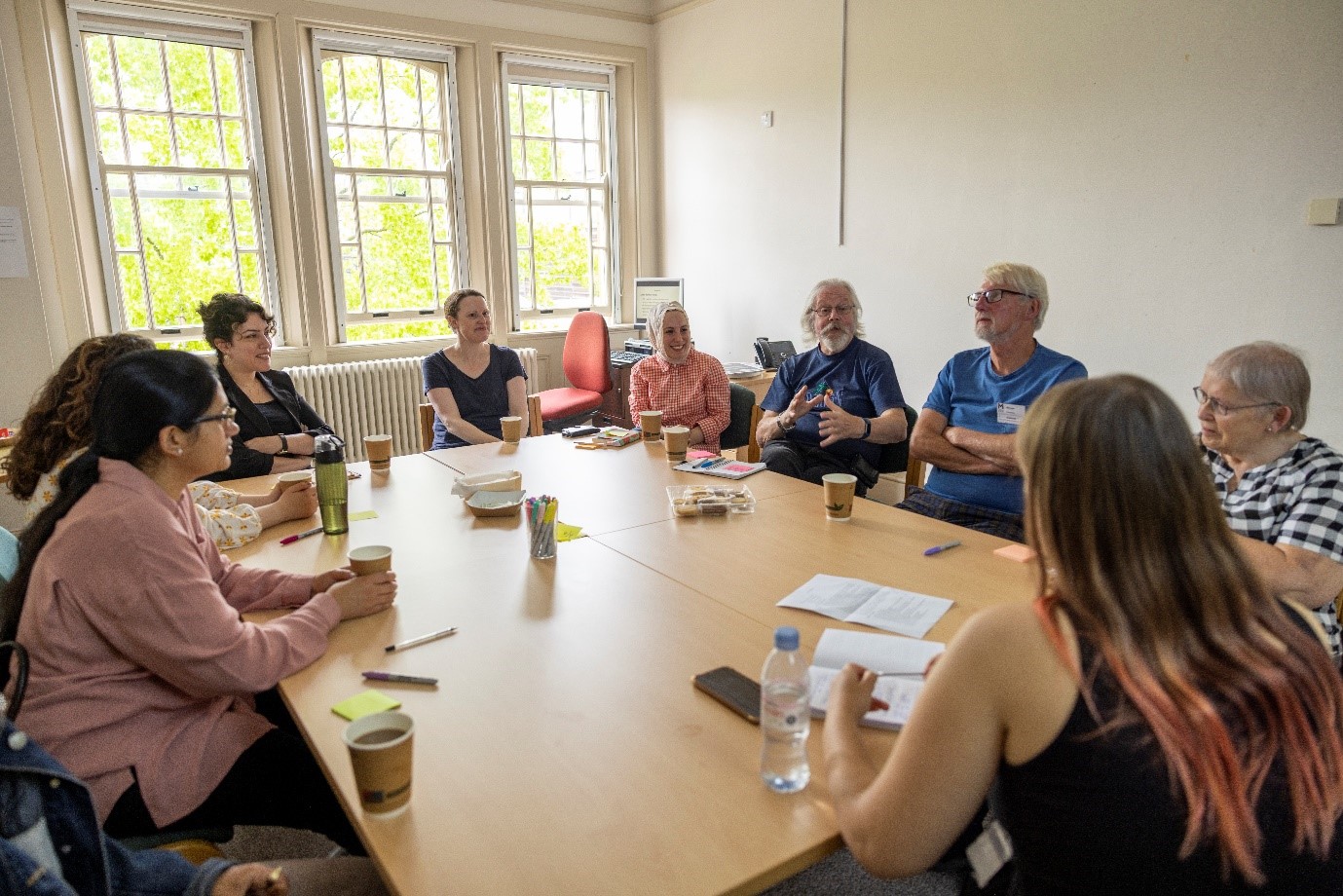 A group of eight MPR volunteers participate in a focus group in a meeting room to advise staff.