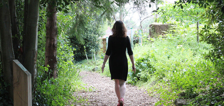 a person walks down a wooded path in the MERL garden
