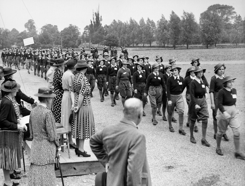 Black and white photograph of an Essex Women's Land Army rally marching past a group of judges including Lady Denman