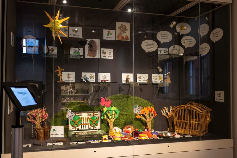 Display case containing museum objects, crafted picnic items and makaton symbols