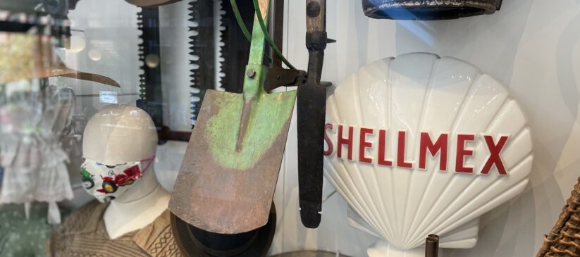A mixture of cultivation and craft objects with a shellmex petrol pump globe and a mannequin in a smock wearing a facemask