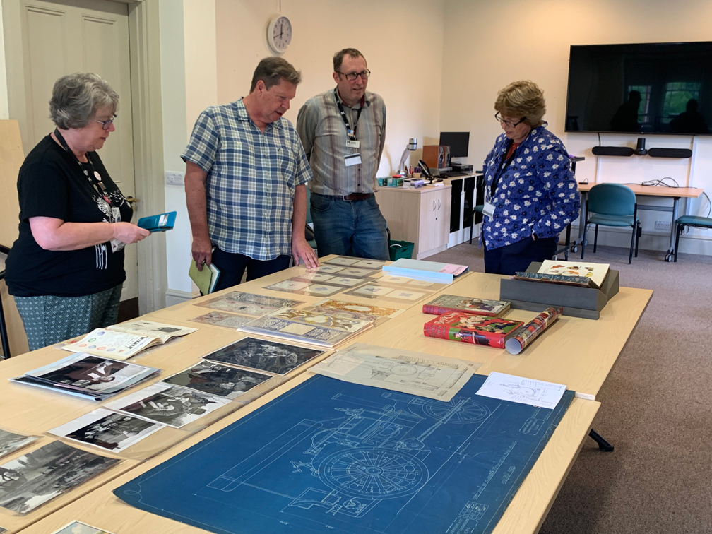 MERL colleagues looking at archives collections laid out on a large table