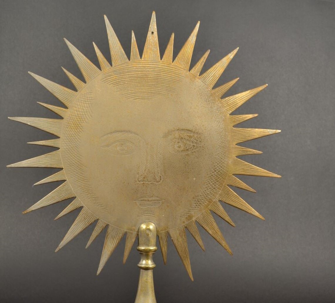 A golden polehead depicting the sun