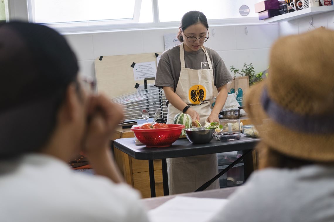 Perle Wong in a kitchen, demonstrating a recipe to onlookers