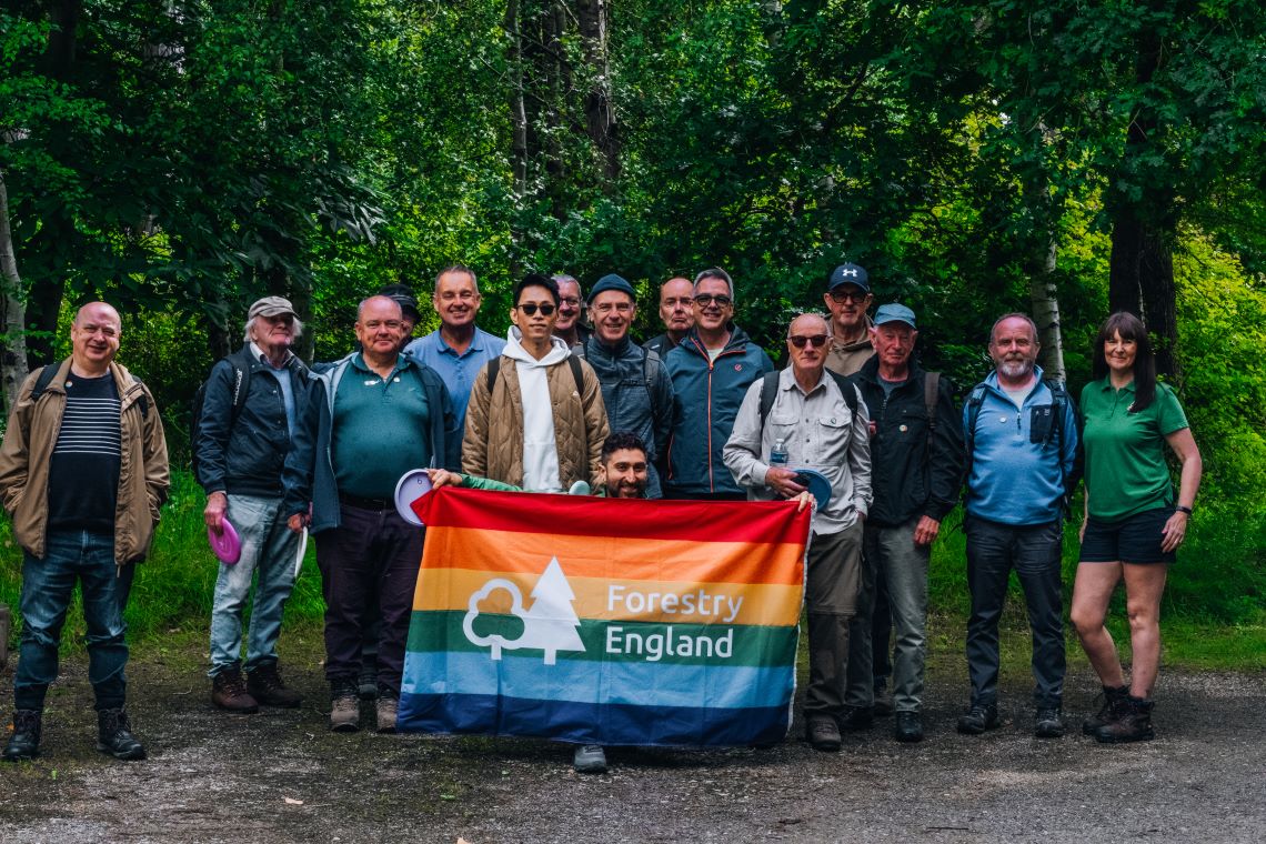 A group of walkers posing for a photo, one of whom has a rainbow flag