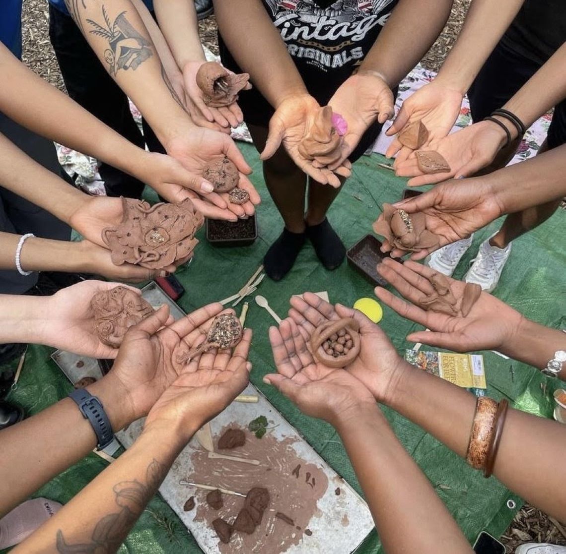 Hands in a circle, each holding clay