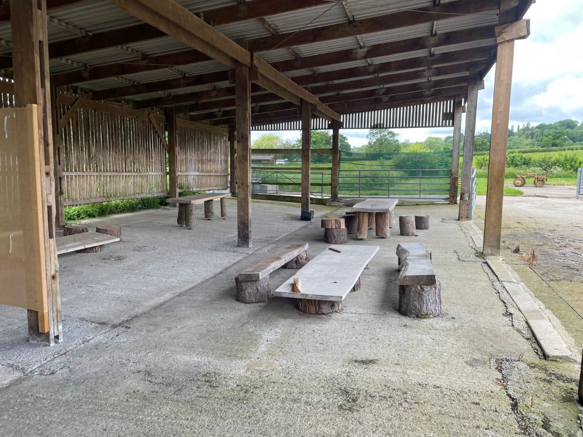 Open walled shed with farm site behind