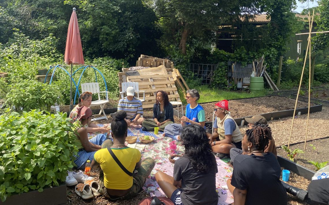 A circle of people sitting in a community garden