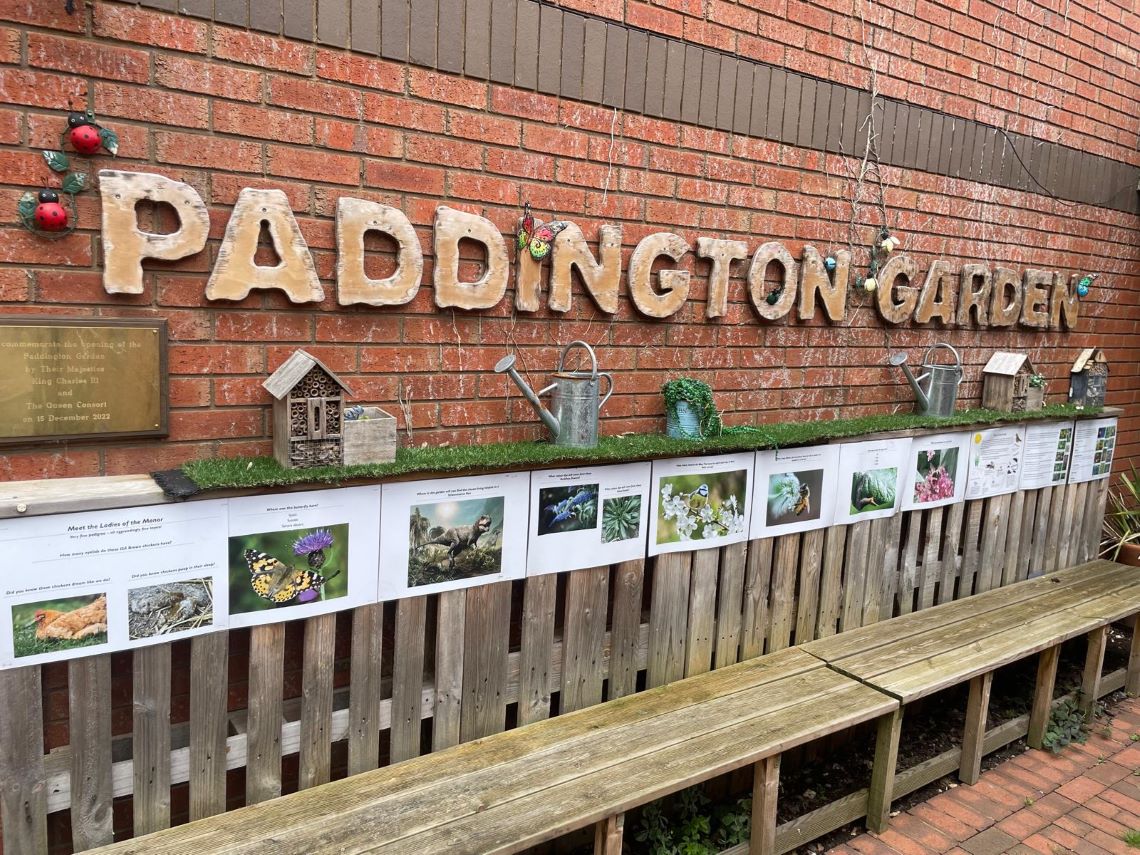 A sign reading "Paddington Garden" with informational panels in front