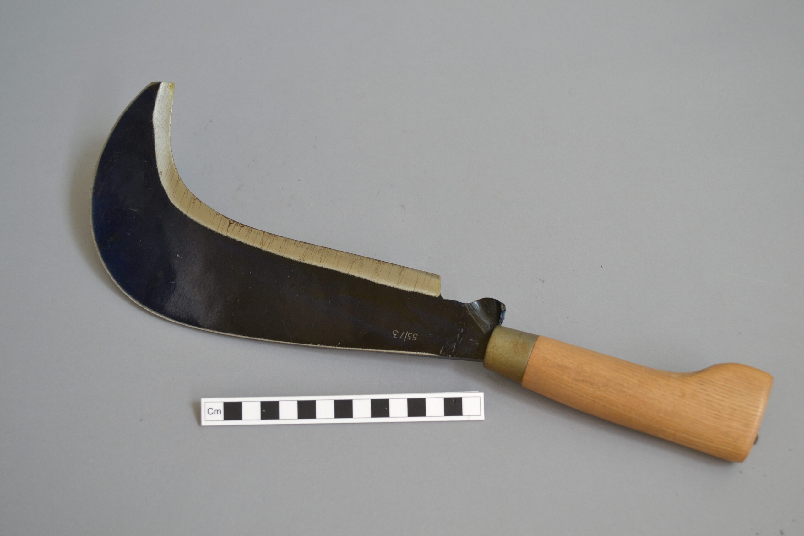 A billhook on a grey background.