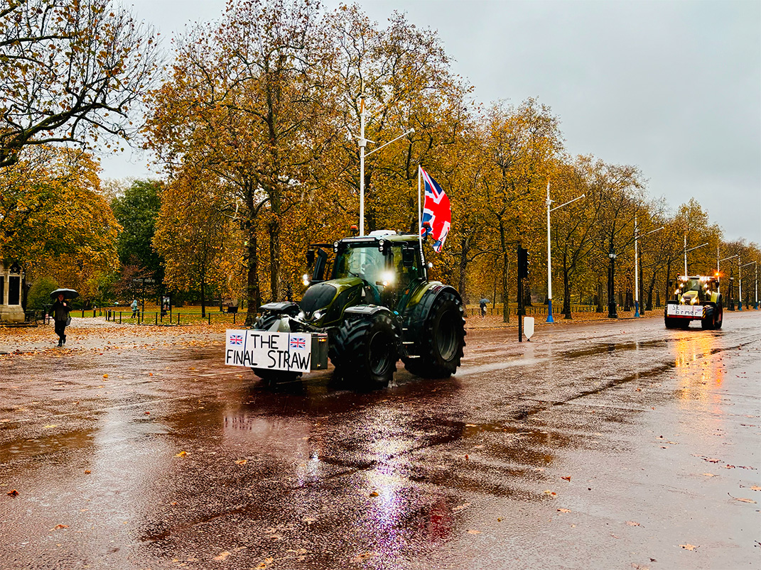 A tractor drives through central London, bearing a sign that says 'The Last Straw'.