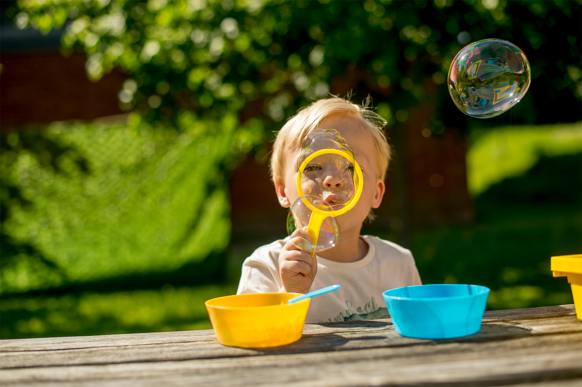 A boy blows a bubble in the garden