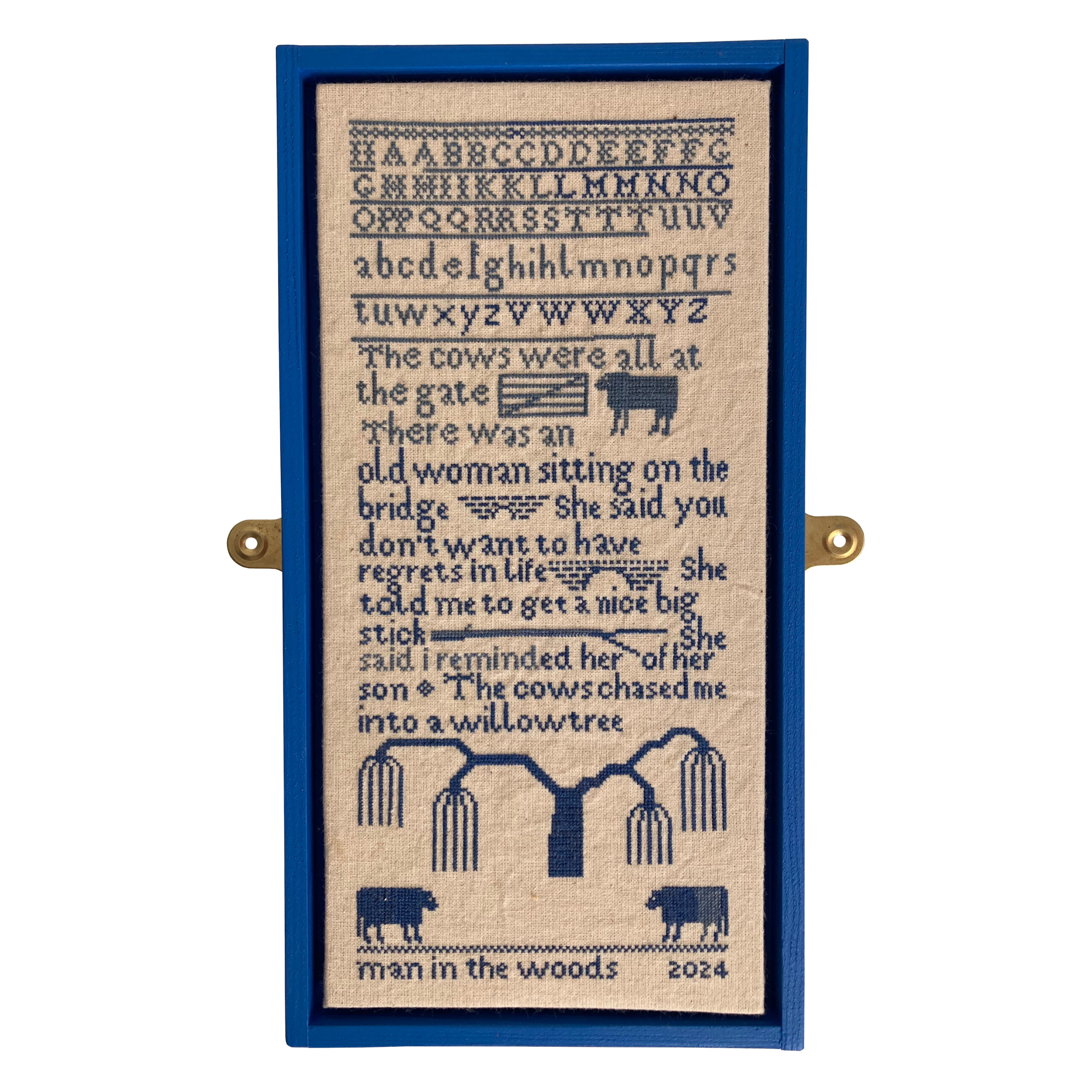 A sampler decorated with trees and cows. It says 'The cows were all at the gate. There was an old woman sitting on the bridge. She said you don't want to have regrets in life. She told me to get a nice big stick. She said I reminded her of her son. The cows chased me into a willow tree.'